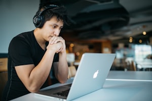 A person working alone on a laptop with headphones on.