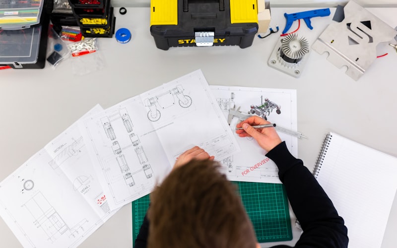 A designer sketching interface layouts on paper next to a laptop.