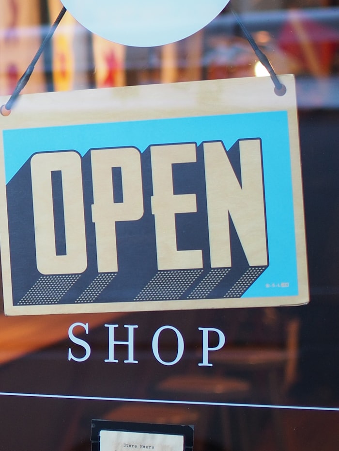 An open sign hanging in the window of a small independent shop.