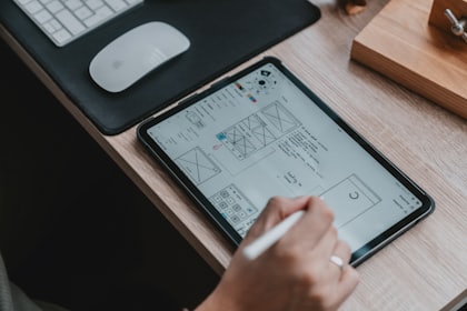 Hands sketching a product layout on a tablet.
