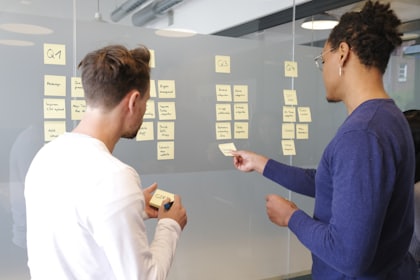Two people mapping out ideas on a wall of sticky notes.