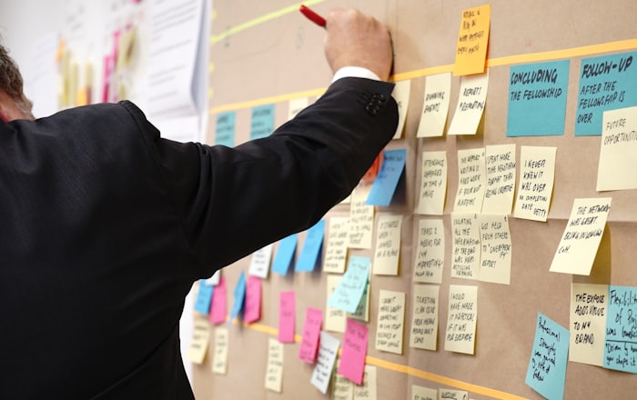 A builder arranging notes and ideas on a glass wall.